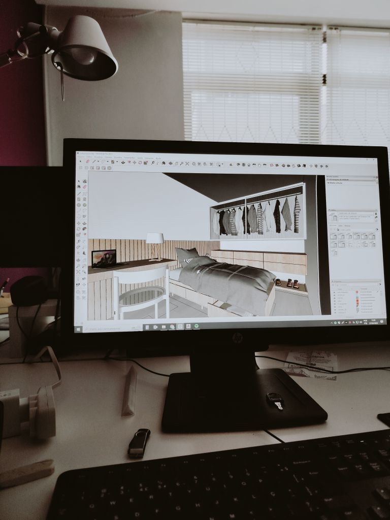 A desktop monitor displaying a 3D room design in a contemporary office setting.