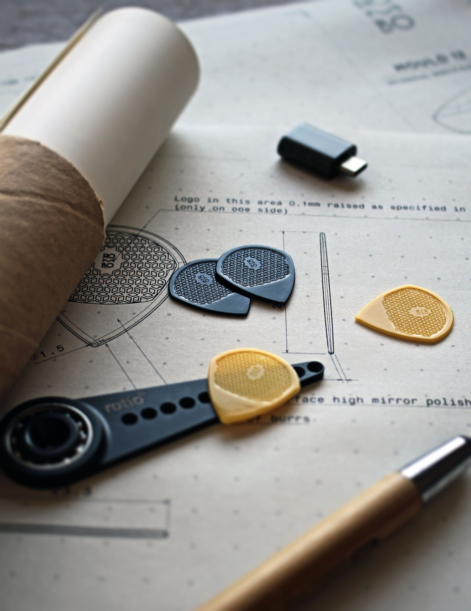 Artistic arrangement of guitar picks on a blueprint paper with design tools for a creative project.