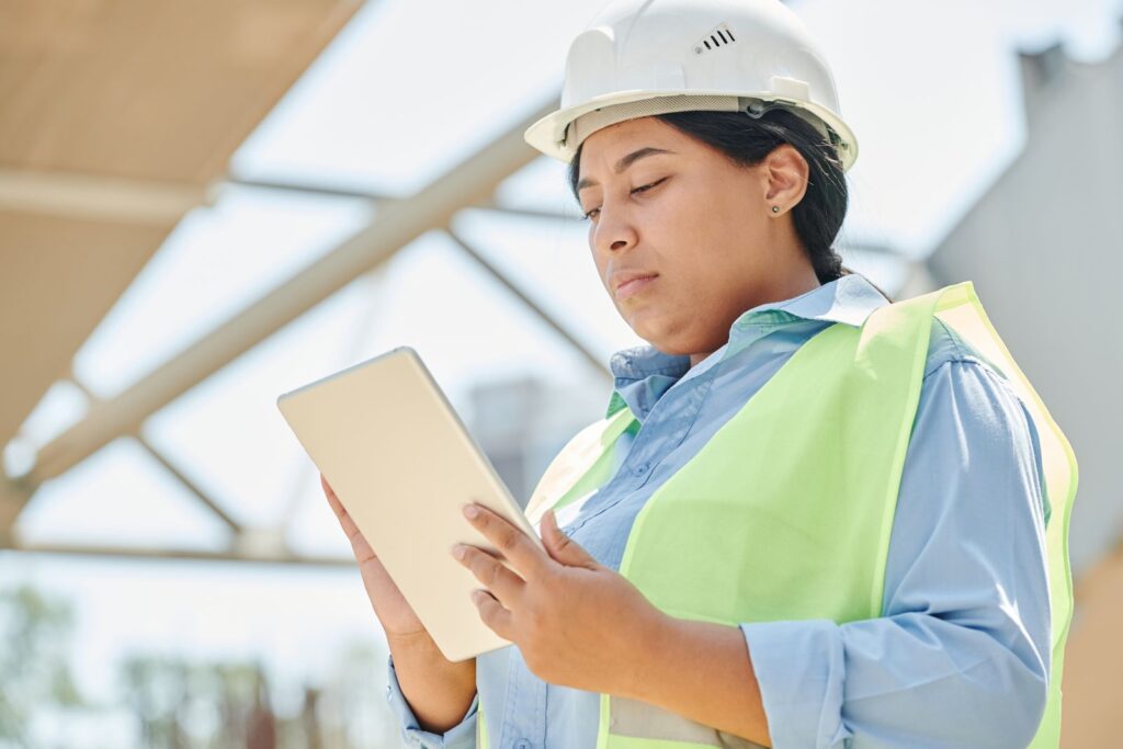 Engineer in a hard hat using a digital tablet at a construction site