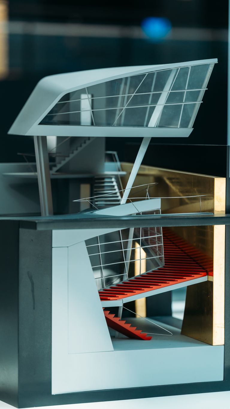 A detailed model of a modern building with a striking red interior staircase and large windows.