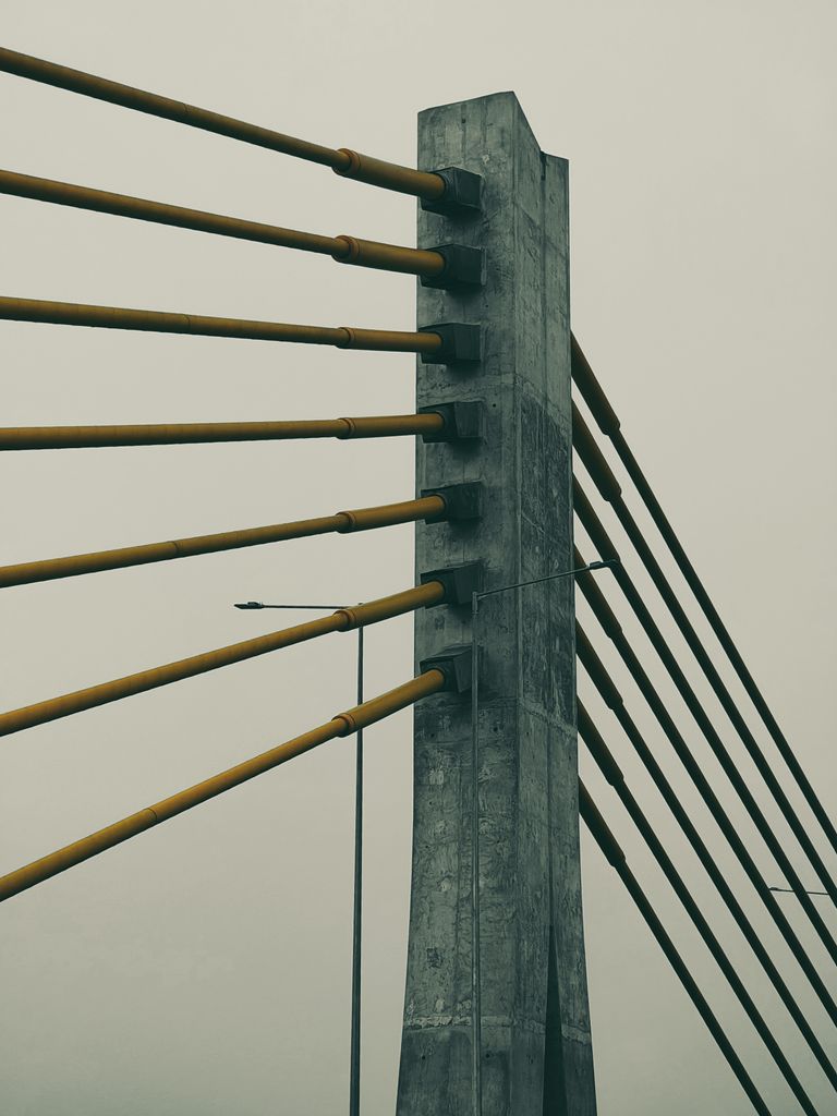 Close-up of a cable-stayed bridge pillar shrouded in fog, highlighting urban architecture.