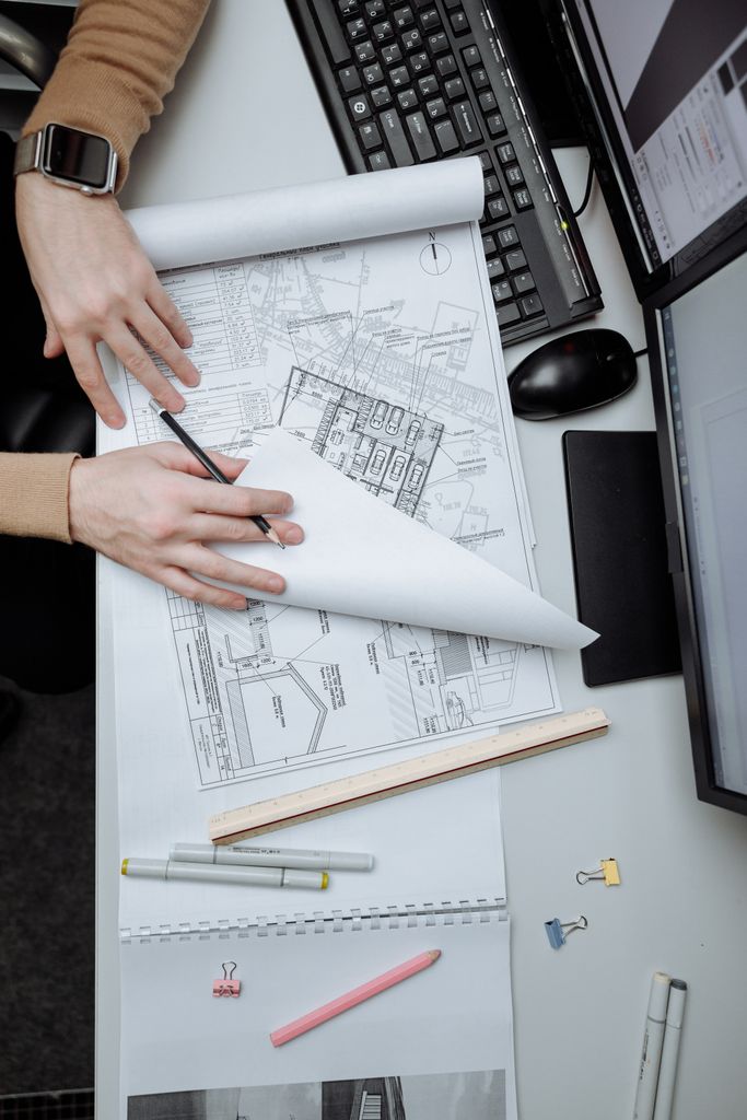 High-angle view of an architect reviewing construction drawings on a desk in an office.