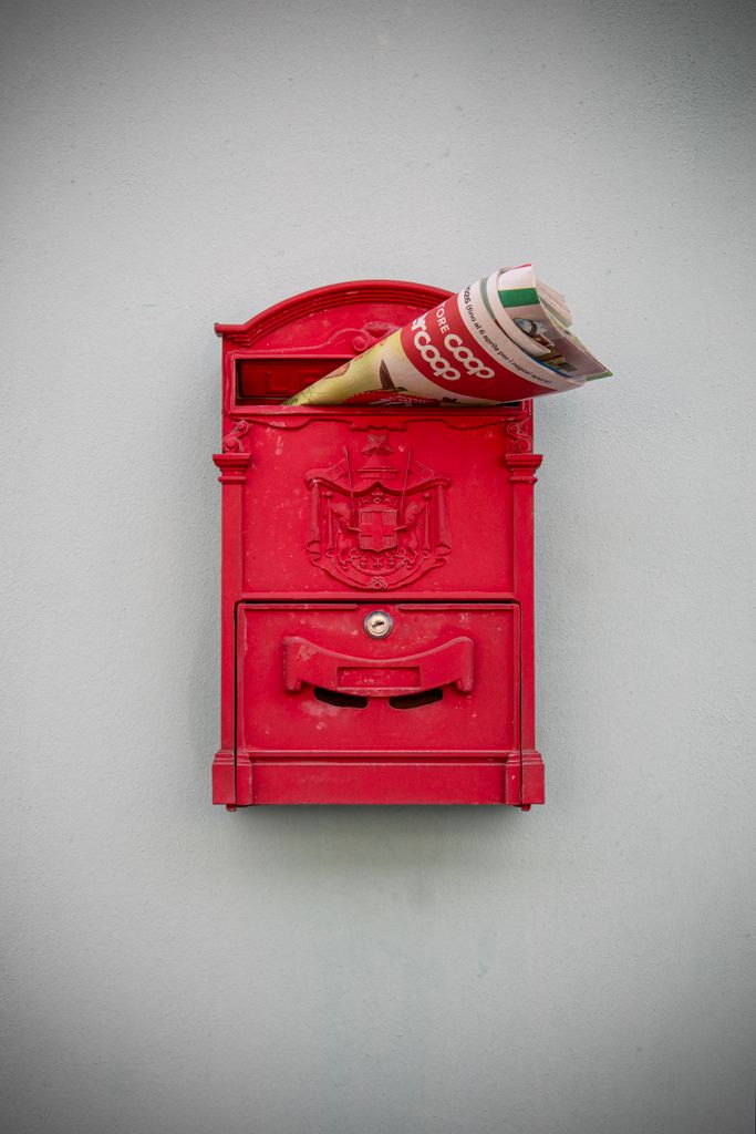 Red mailbox with a newspaper in Palmanova, Italy. Italian architecture style.