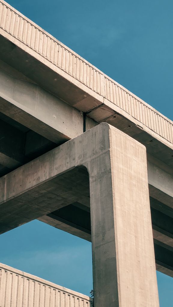 Urban architectural angle showing concrete overpass with clear blue sky. Ideal for modern infrastructure themes.