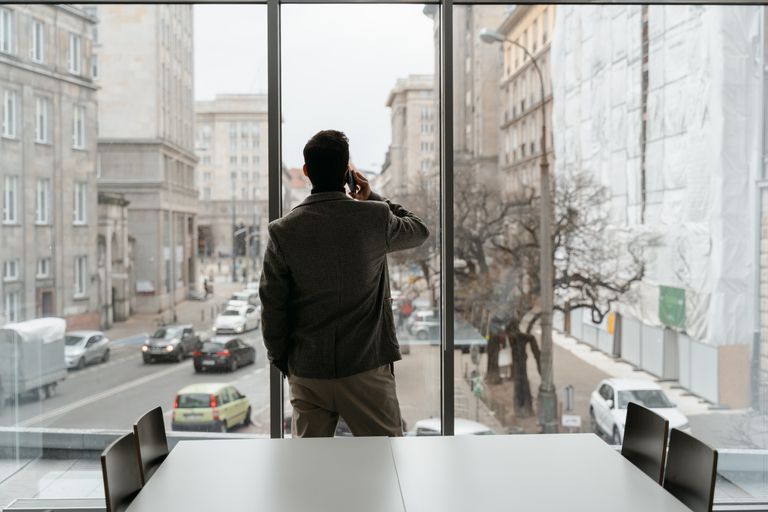 Professional man making a phone call while looking out of an urban office window.