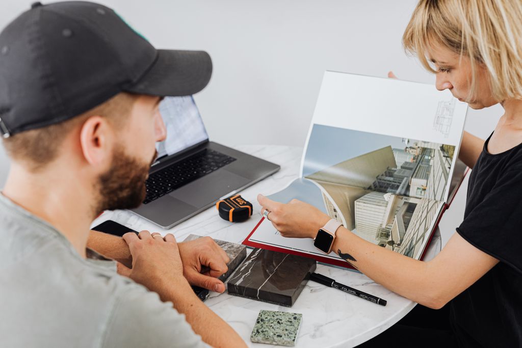 Two interior designers discussing architectural plans in an office setting.