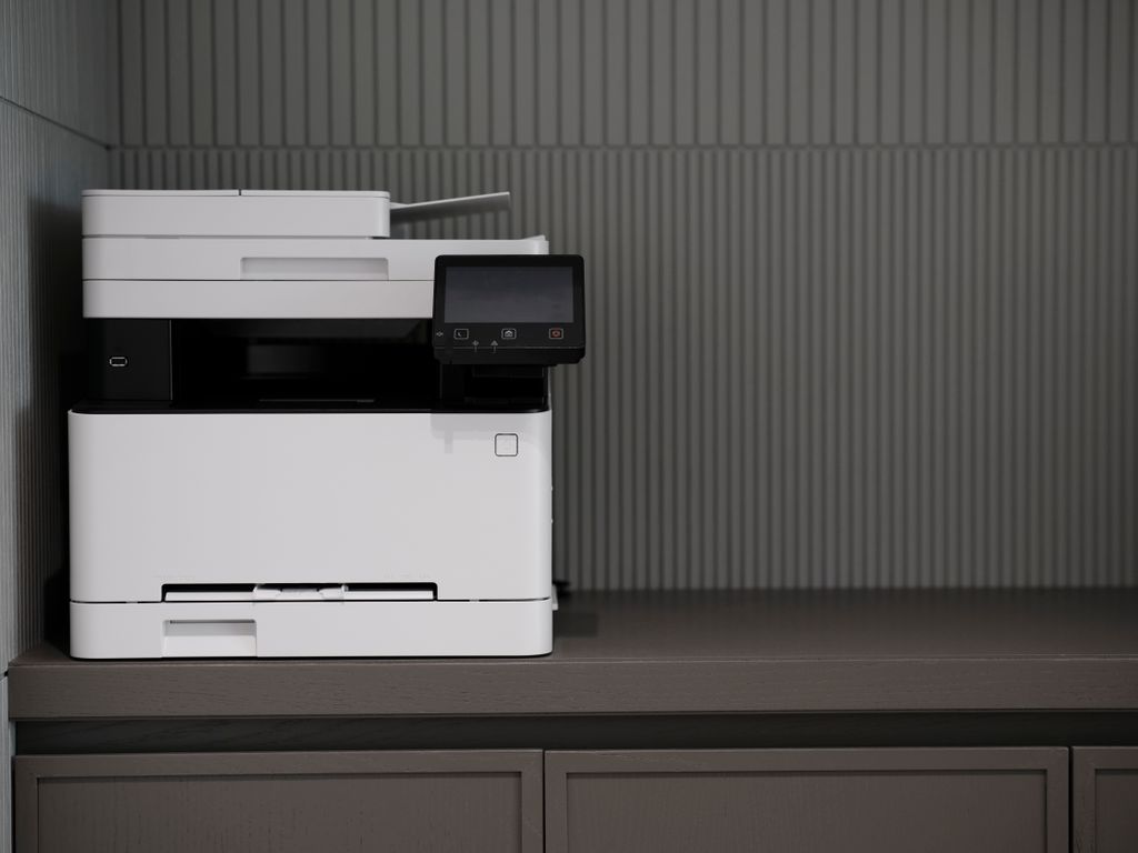 A sleek, modern printer situated on a minimalist office desk with a textured background.